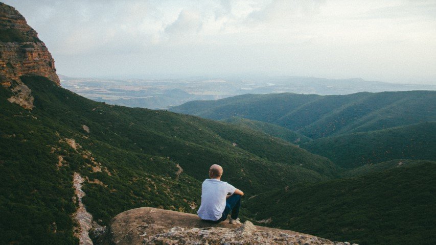 Man sitting on a mountain due to living an active lifestyle